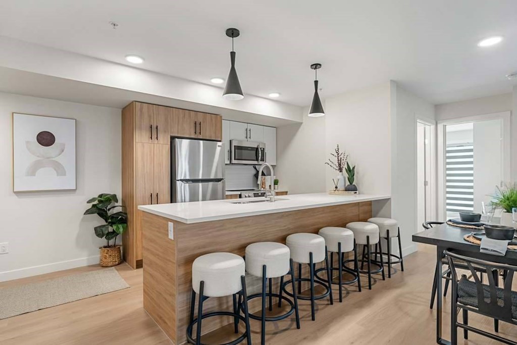 A modern kitchen with white countertops and stools.at Skyway Apartments, Calgary, AB