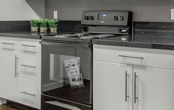 A modern kitchen with a black countertop and white cabinets.
