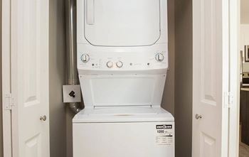 A white dryer is installed in a narrow space between two doors.
