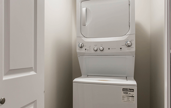 A white dryer is sitting in a bathroom next to a white door.
