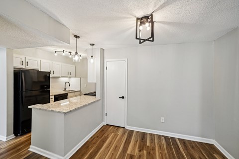 A kitchen with a black refrigerator and white cabinets.