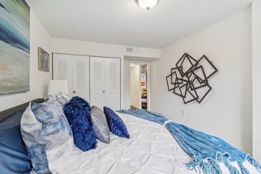 a bedroom with white walls and a bed with blue blankets and pillows at Oaks at Oxon Hill, Oxon Hill, Maryland