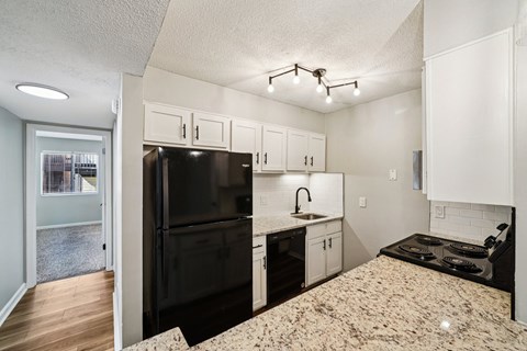 A kitchen with a black refrigerator and white cabinets.