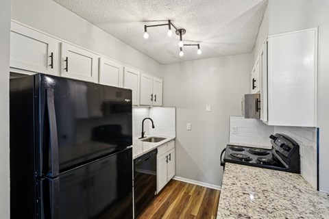 A black fridge and stove in a small kitchen.