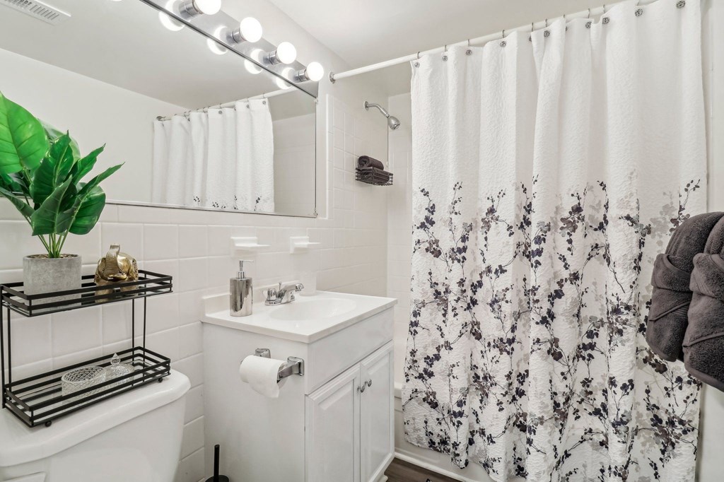 a white bathroom with a shower curtain and a sink at Oaks at Oxon Hill, Oxon Hill, Maryland