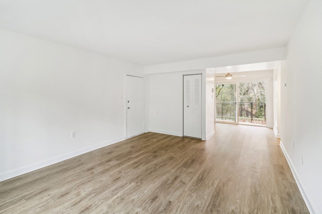 an empty living room with white walls and wood floors at Oaks at Oxon Hill, Oxon Hill, Maryland