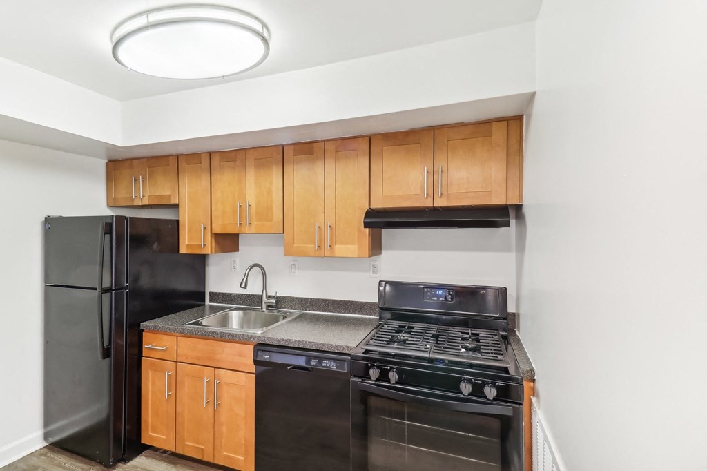 a kitchen with black appliances and wooden cabinets and a black refrigerator at Oaks at Oxon Hill, Oxon Hill, Maryland