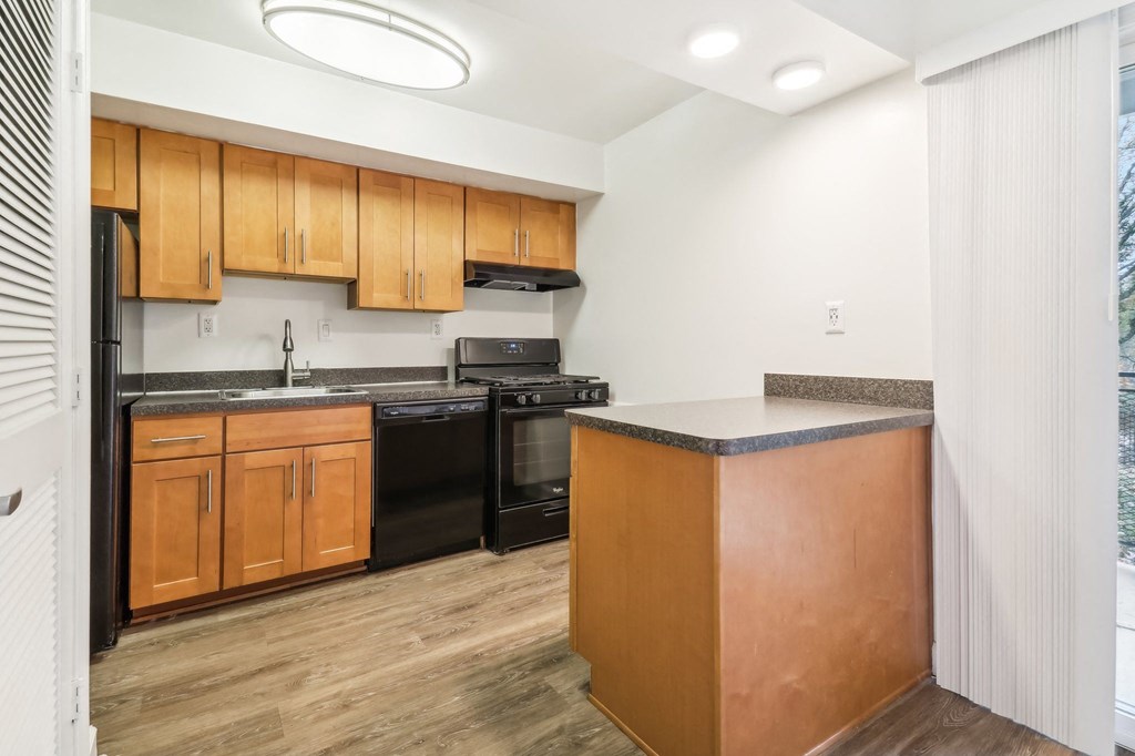 a kitchen with black appliances and wooden cabinets and a counter top at Oaks at Oxon Hill, Oxon Hill, Maryland