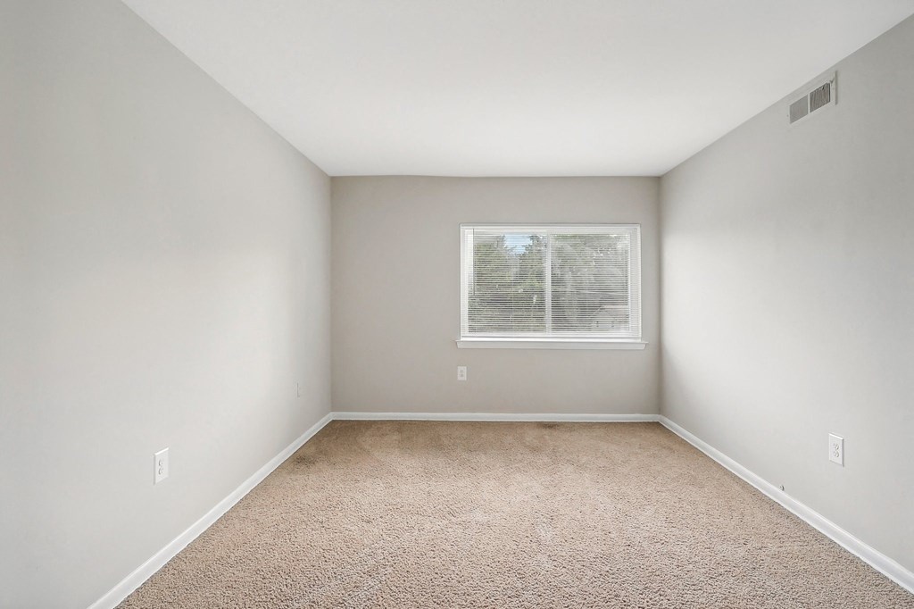 an empty room with carpet and a window at Andrews Ridge Apartments, Suitland, MD