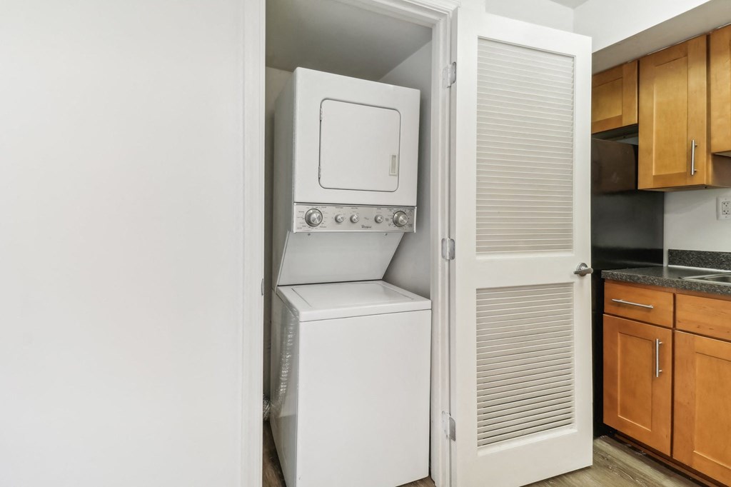 a white washer and dryer in a kitchen with wood cabinets at Oaks at Oxon Hill, Oxon Hill, Maryland