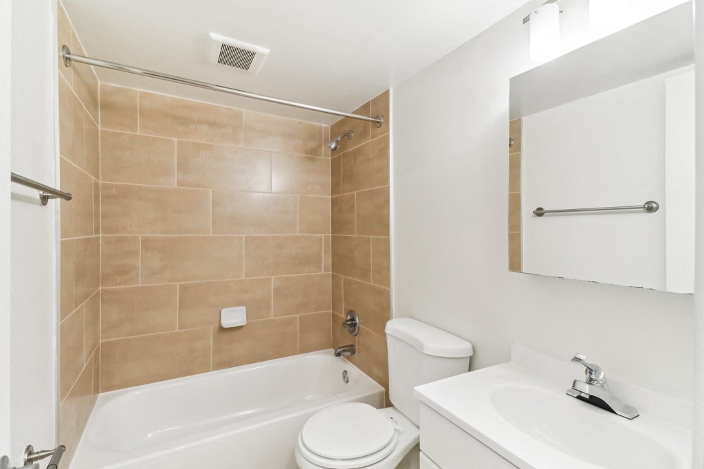 a bathroom with a toilet sink and tub and a mirror at Oaks at Oxon Hill, Oxon Hill, Maryland