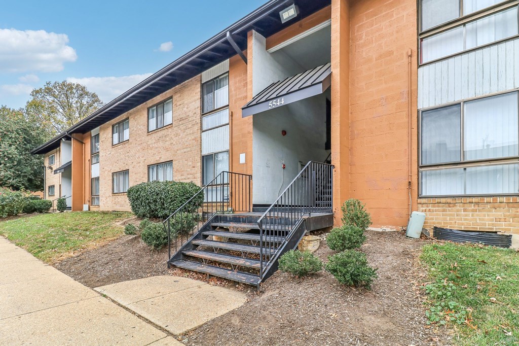 an apartment building with stairs and a sidewalk in front of it at Oaks at Oxon Hill, Oxon Hill, Maryland