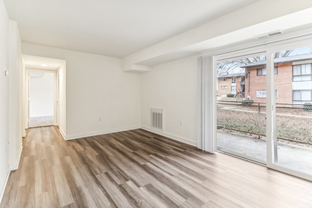 an empty living room with wood flooring and a large window at Oaks at Oxon Hill, Oxon Hill, Maryland