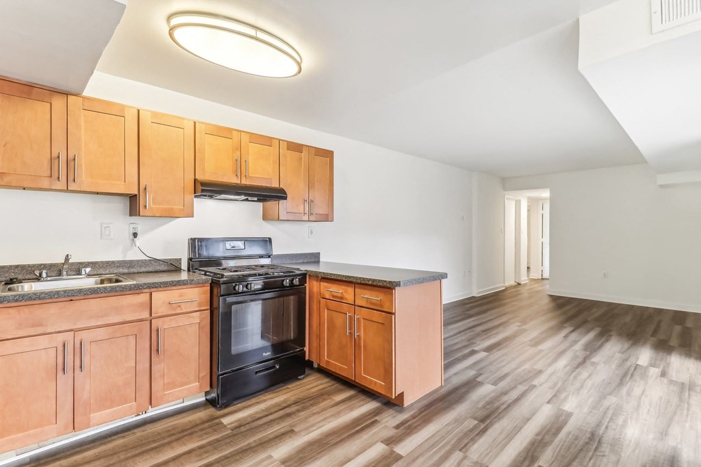 a kitchen with wooden cabinets and a stove and a sink at Oaks at Oxon Hill, Oxon Hill, Maryland