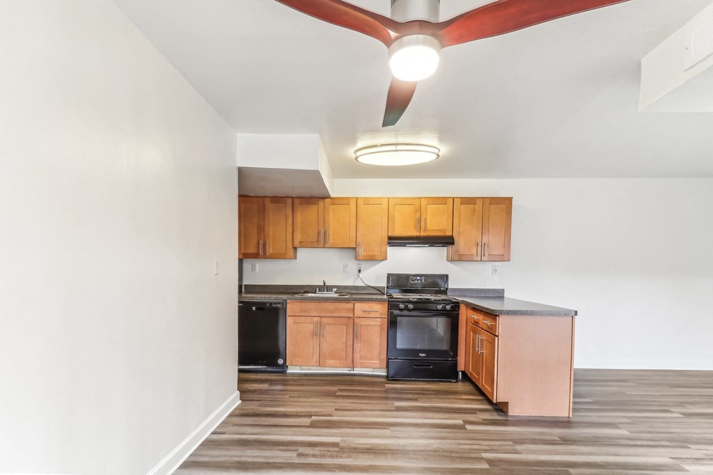 a kitchen with wooden cabinets and black appliances and a ceiling fan at Oaks at Oxon Hill, Oxon Hill, Maryland