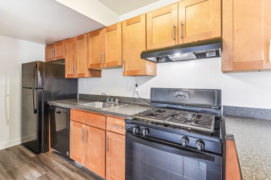 a kitchen with black appliances and wooden cabinets at Oaks at Oxon Hill, Oxon Hill, Maryland