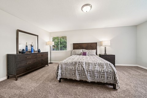 A bedroom with a bed, dresser, and mirror.