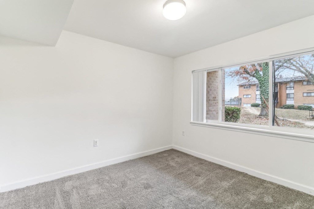 an empty living room with a large window and carpet at Oaks at Oxon Hill, Oxon Hill, Maryland