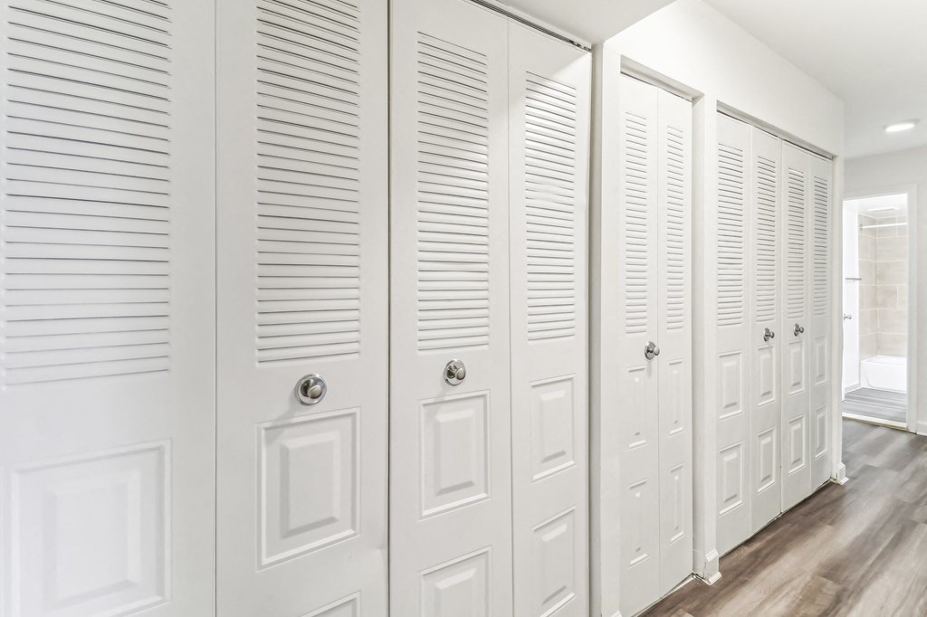 a row of white closet doors in a room with wood floors at Oaks at Oxon Hill, Oxon Hill, Maryland