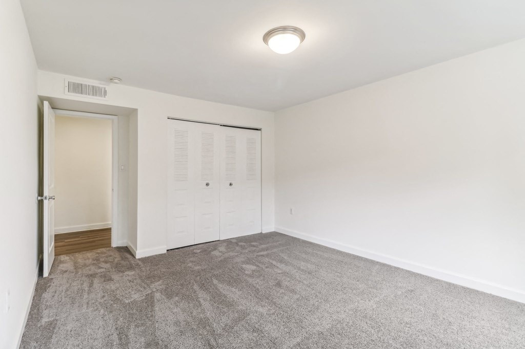 a living room with carpet and a door to a closet at Oaks at Oxon Hill, Oxon Hill, Maryland
