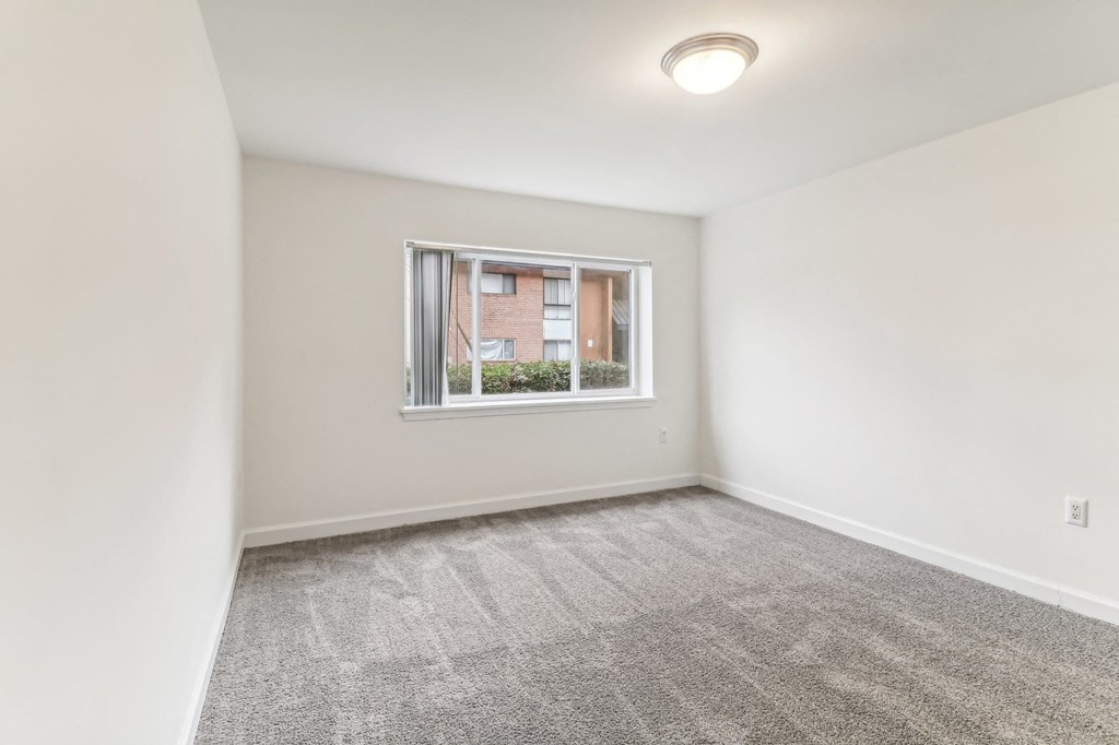 an empty living room with a window and white walls at Oaks at Oxon Hill, Oxon Hill, Maryland