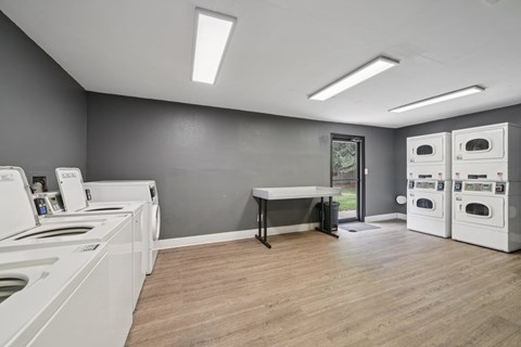 A laundry room with washers and dryers and a table.