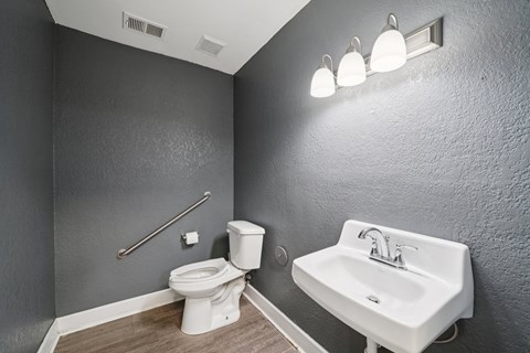 A bathroom with a toilet, sink, and lights.