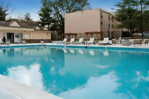 A swimming pool with lounge chairs and a building in the background.