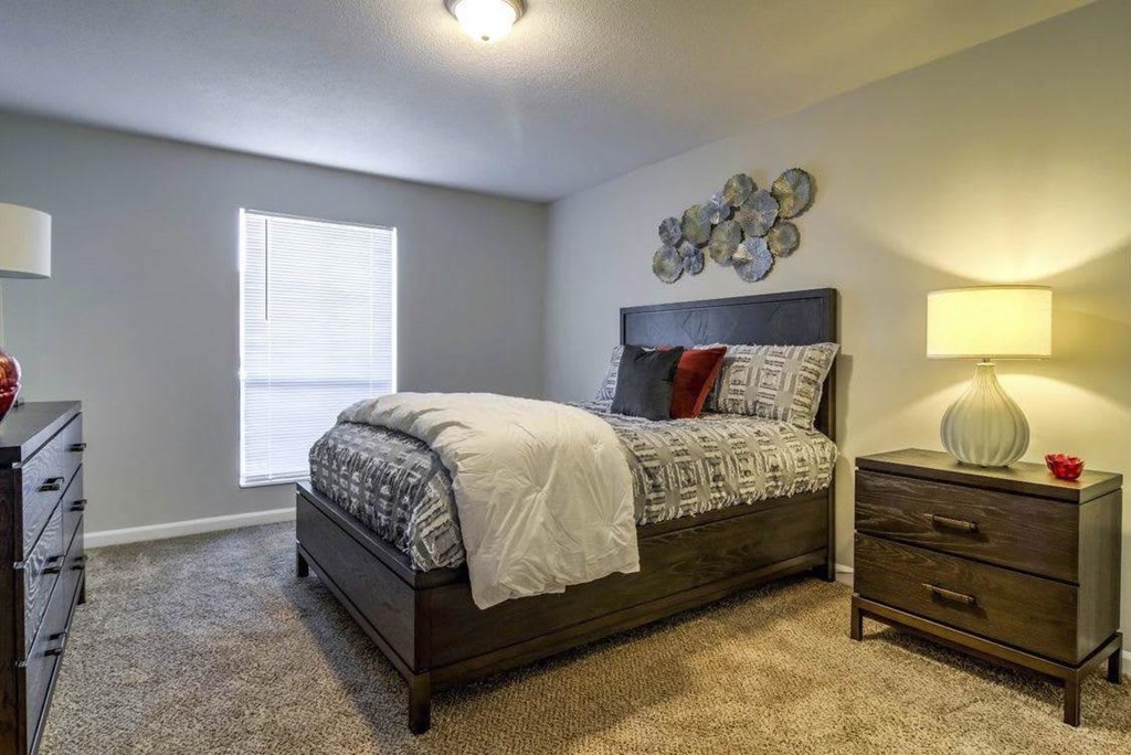 A bedroom with a bed, nightstand, and lamp at The Onyx Hoover Apartments, Hoover
