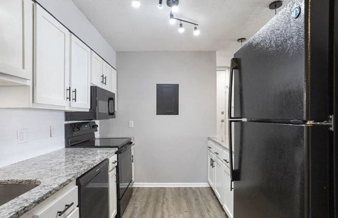 A black refrigerator is on the right side of a kitchen at The Onyx Hoover Apartments, Hoover, AL