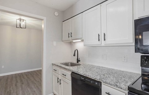 A kitchen with white cabinets and a granite countertop at The Onyx Hoover Apartments, Alabama, 35216