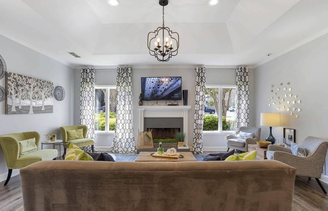 A living room with a brown couch and a chandelier.
