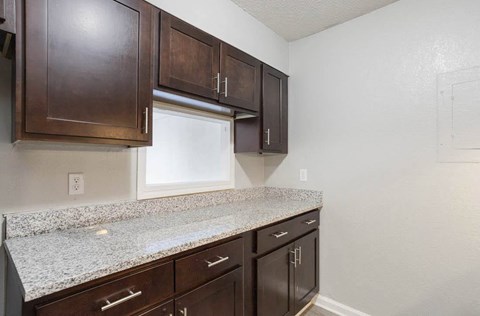 A kitchen with brown cabinets and granite countertops at The Onyx Hoover Apartments, Hoover, AL