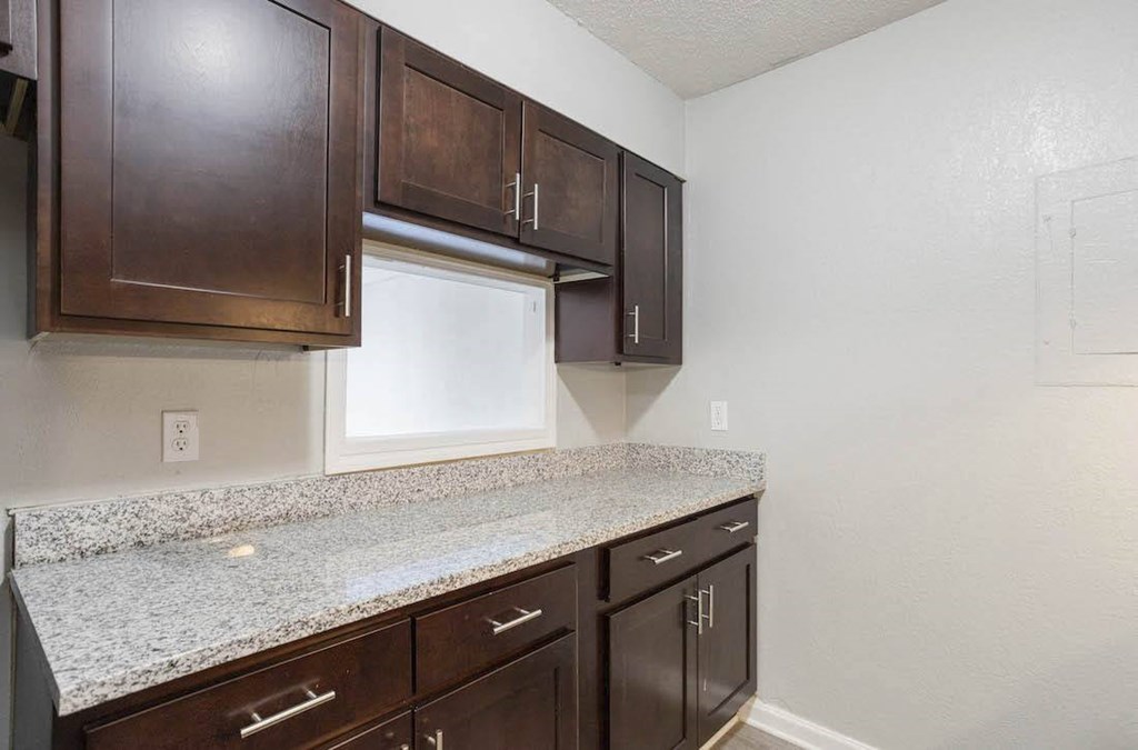 A kitchen with brown cabinets and granite countertops. A kitchen with brown cabinets and granite countertops at The Onyx Hoover Apartments, Hoover, AL