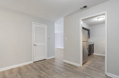 A room with a white door and a kitchen area in the background. at The Onyx Hoover Apartments, Hoover, AL