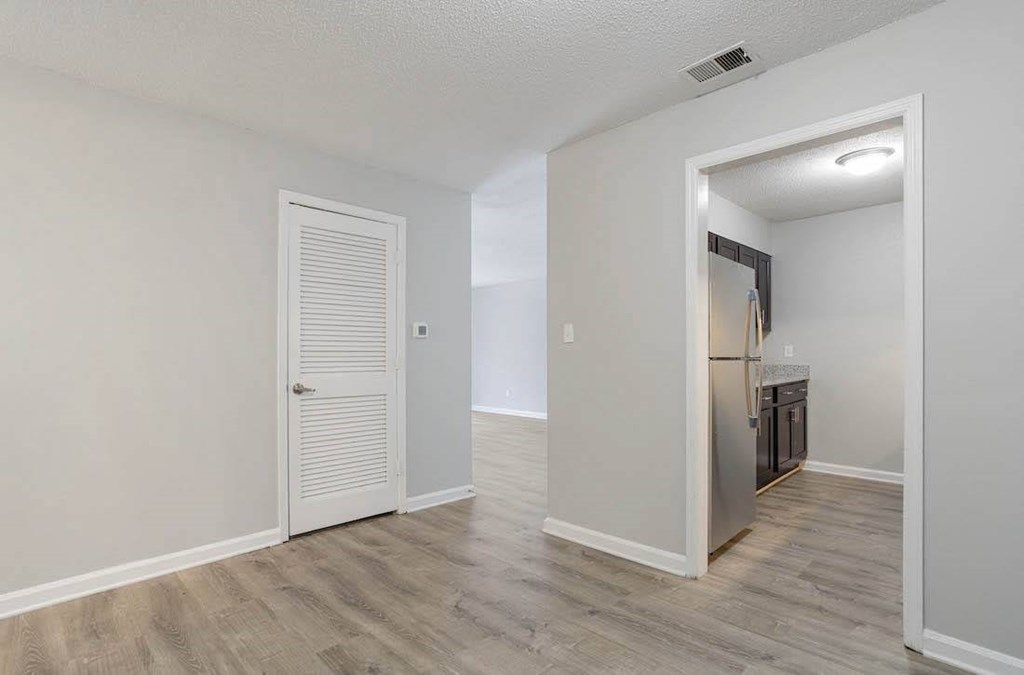 A room with a white door and a kitchen area in the background. A room with a white door and a kitchen area in the background. at The Onyx Hoover Apartments, Hoover, AL
