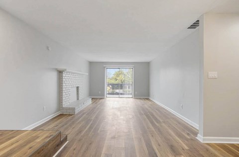 A spacious room with wooden flooring and a brick fireplace. at The Onyx Hoover Apartments, Alabama, 35216