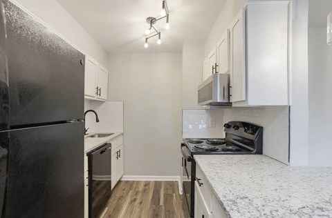 A kitchen with a black refrigerator and white cabinets. at The Onyx Hoover Apartments, Hoover, AL, 35216