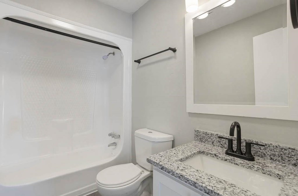 A white toilet sits next to a sink in a bathroom. A white toilet sits next to a sink in a bathroom at The Onyx Hoover Apartments, Hoover, AL