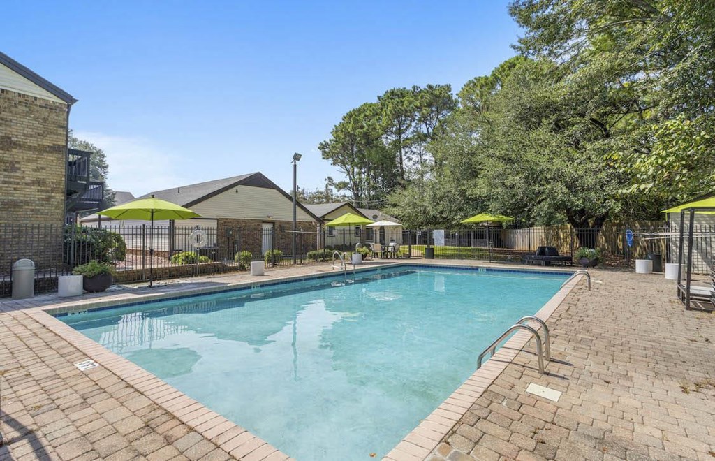 A large outdoor swimming pool surrounded by a brick patio and trees. A large outdoor swimming pool surrounded by a brick patio and trees at The Onyx Hoover Apartments, Hoover, 35216
