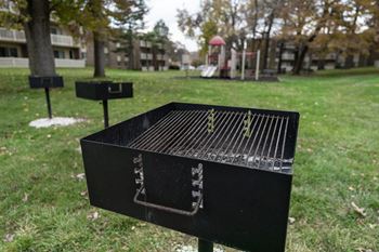 a grill with a playground in the background at The Glendale Residence Apartments, Lanham, MD