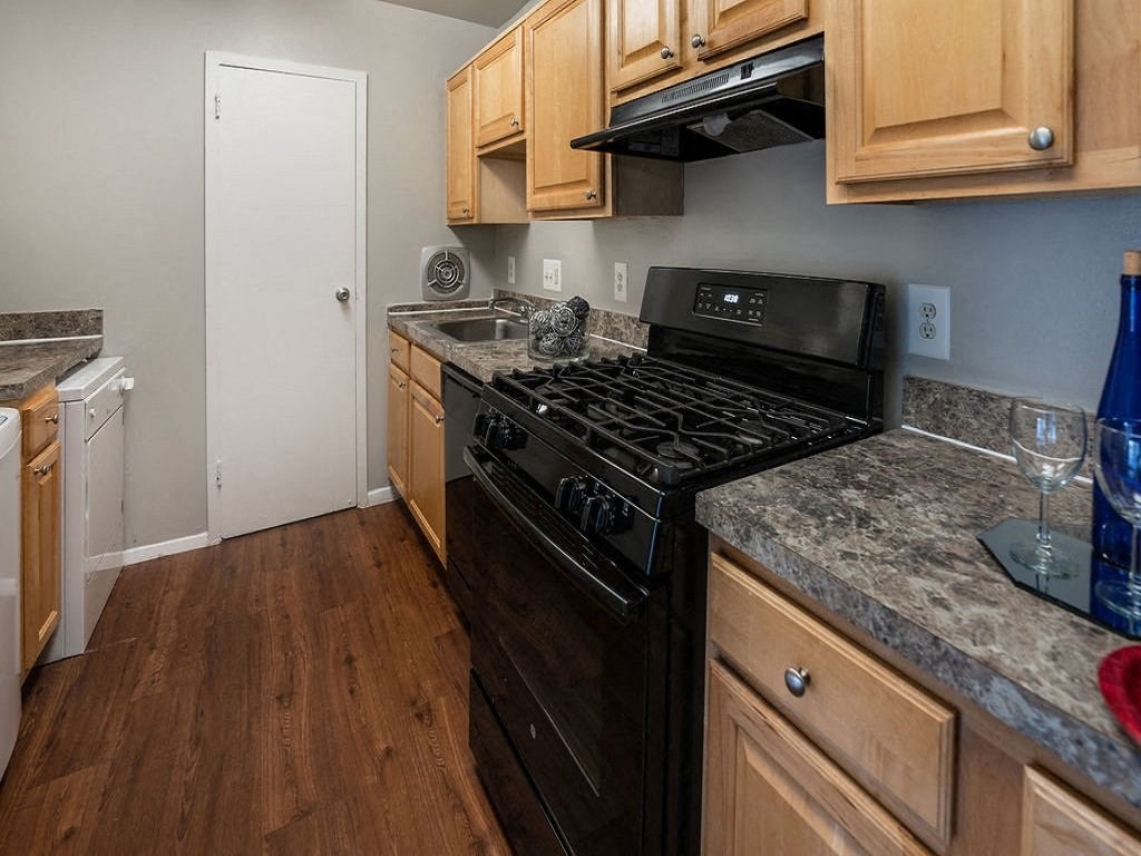 a kitchen with wooden cabinets and a black stove top oven at The Glendale Residence, Maryland