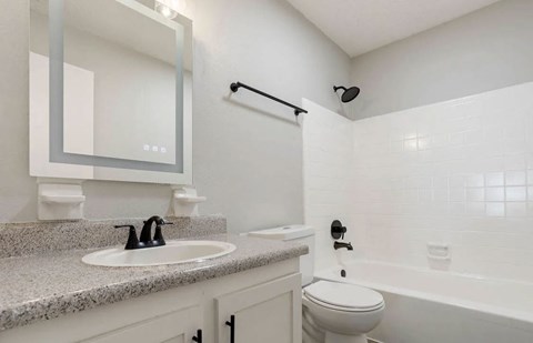 A white bathroom with a sink, toilet, and bathtub at The Onyx Hoover Apartments, Hoover, 35216