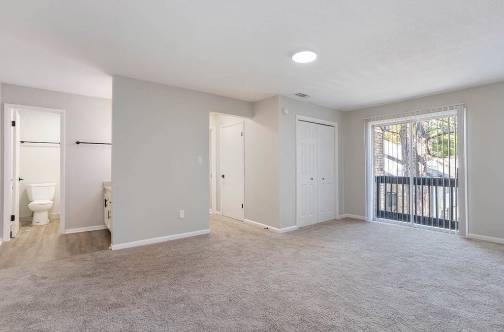 A spacious room with a carpeted floor and a sliding glass door leading to a balcony. A spacious room with a carpeted floor and a sliding glass door leading to a balcony at The Onyx Hoover Apartments, Alabama, 35216