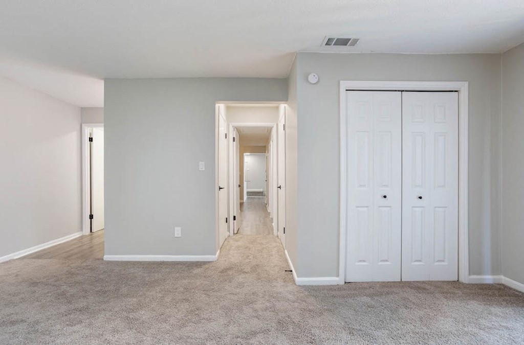 A long hallway with white doors and carpeted floors. A long hallway with white doors and carpeted floors at The Onyx Hoover Apartments, Hoover, AL, 35216