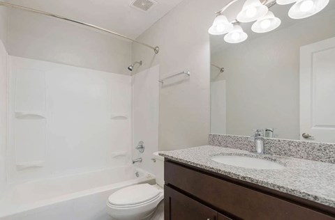 A white toilet sits next to a white sink in a bathroom at The Onyx Hoover Apartments, Hoover, AL, 35216