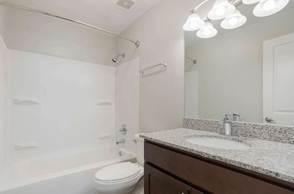 A white toilet sits next to a white sink in a bathroom. A white toilet sits next to a white sink in a bathroom at The Onyx Hoover Apartments, Hoover, AL, 35216