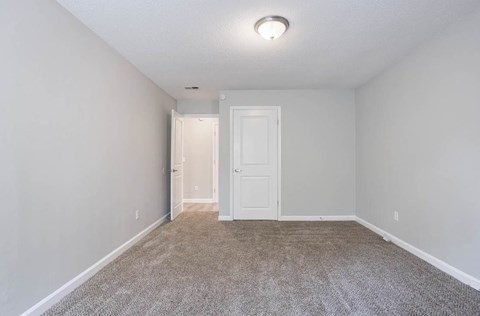 A room with a carpeted floor and a white door at The Onyx Hoover Apartments, Hoover, AL, 35216