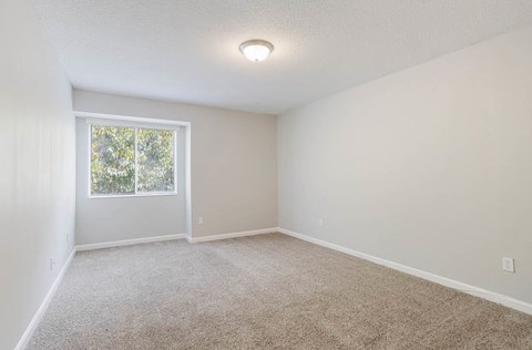 A room with a carpeted floor and a window at The Onyx Hoover Apartments, Hoover, AL