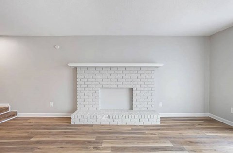 A white brick fireplace in a room with wooden floors at The Onyx Hoover Apartments, Alabama, 35216